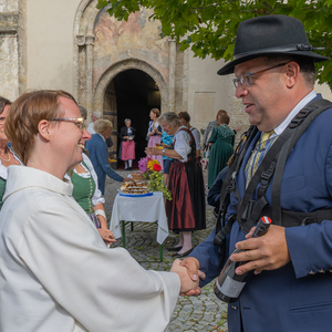 Dankefest in der Pfarre Kirchdorf an der Krems, BIld: Martin Buchegger, Obmann der Stadtkapelle, wünscht der scheidenden Pastoralassistentin Bernadette Hackl alles Gute, im Hintergrund sorgen Frauen der Trachtengruppe für die Agape